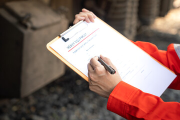 Wall Mural - action of a mechanic engineer is checking on heavy machine checklist form to verify the quality of m