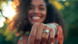 close-up photography capturing a joyful moment of a woman showcasing her engagement ring. The focus is sharply on the dazzling diamond ring perched on her finger