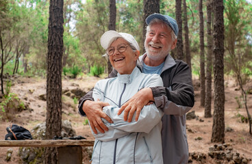 Sticker - Happy senior couple hugging in the woods enjoying mountain hike appreciating nature and freedom, retired seniors man and woman and healthy lifestyle concept