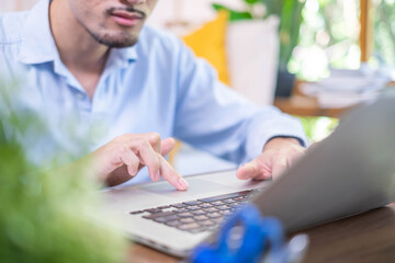 Wall Mural - Close-up freelance businessman working at indoors home office typing hand on desk computer laptop internet communication technology, human hand adult business person using laptop keyboard notebook