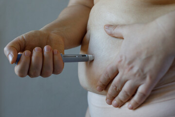 Wall Mural - Semaglutide or insulin Injection closeup. Female model making Semaglutide Injection Pen in her Stomach. Semaglutide Diabetes Drug Being Used For Weight Loss.