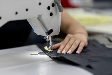 female dressmaker working on the factory using sewing machine close up shot