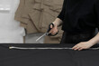 © Mihail - female tailor cutting fabric with scissors in the office