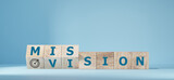 Fliped wooden cubes vision to a mission. Dice form the words vision and mission.