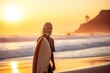 Portrait of senior man with surfboard on the beach at sunset. Sport concept. Vacation and Travel Concept with Copy Space.