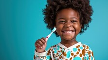A Young Girl With A Big Smile Holding A Toothbrush Standing Against A Vibrant Blue Background Wearing A Polka Dot Top.