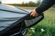 person unfolding a car cover to protect against future bird droppings