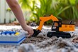 kid positioning toy excavator near lego building site