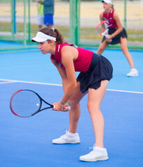 Wall Mural - A girl plays tennis on a court with a hard blue surface on a summer sunny da