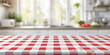 an empty table with a red and white checkered tablecloth on a blurred background of a light kitchen