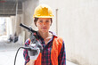 © Robert Kneschke - Portrait of confident young female construction worker wearing workwear carrying equipment at site