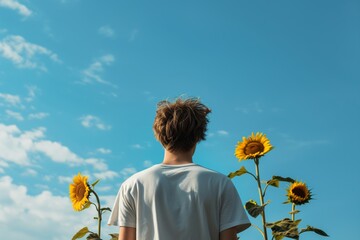 Poster - casualdressed male with sunflowers against blue sky