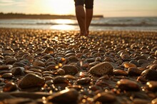 A Person Walking On A Beach With Rocks At Sunset And Bank Of Beach