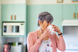 © Austockphoto - Older woman drinking a warm tea beverage in pastel kitchen