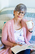 © Austockphoto - Happy woman reading a book while drinking a cuppa tea