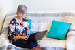 © Austockphoto - senior woman working on laptop on lounge with a cup of tea