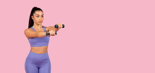 Wall Mural - Focused woman exercising with dumbbells on pink, panorama