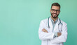 A smiling male doctor in a white coat with a stethoscope stands confidently with his arms crossed against a turquoise background, exuding professionalism and friendliness.