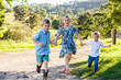 © Austockphoto - Three siblings running down the farm driveway, playing a game together