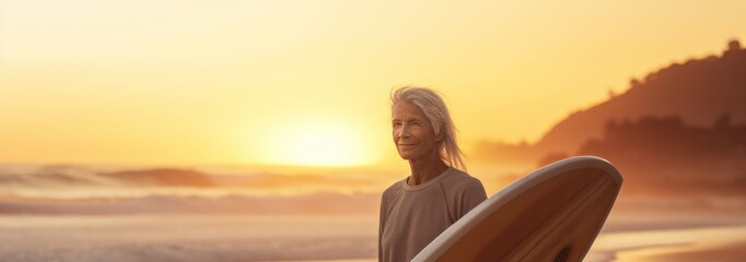 Wall Mural - Portrait of senior woman with surfboard on the beach at sunset. Sport concept. Vacation and Travel Concept with Copy Space.