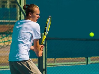 Wall Mural - Tennis player playing tennis on a hard court on a bright sunny day	