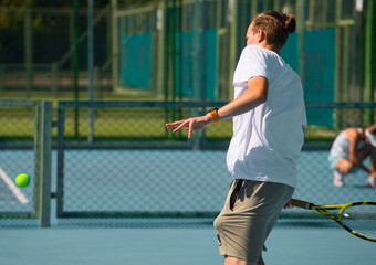 Wall Mural - Tennis player playing tennis on a hard court on a bright sunny day	