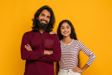 Wall Mural - Positive young indian man and woman posing on yellow background