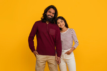 Wall Mural - Happy young indian couple posing on yellow background