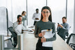 © standret - In front of colleagues. Woman is standing. Team of office workers are together indoors