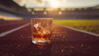 Cinematic wide angle photograph of two whisky glasses at a running track. Product photography.