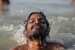 A devotee indian man peacefully floats in the water, his eyes closed and completely relaxed.