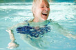 © MACO - Older woman in an indoor pool doing water gymnastics and laughing