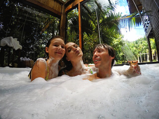 Wall Mural - familia feliz em spa relaxante, jacuzzi com espumas 