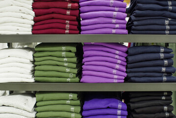 Wall Mural - Pile of different colors of t-shirts with size sticker on shelves in a store 