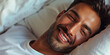 Joyful Latino Man Lying in Bed. Close-up portrait of smiling man lying in bed, background for bedding store.