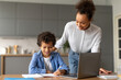 © Prostock-studio - Mother helps son with homework on laptop at home