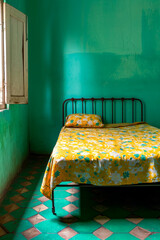 Sticker - Single bed with yellow flowered blanket and blue wall behind it.