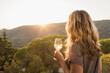 © MACO - Woman standing in the evening sun drinking champagne with Italian landscape in the background. Elba Island, Italy