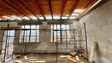 Fototapeta Krajobraz - House building in progress - raw brick and concrete walls with window holes, wooden ceiling and scaffoldings.