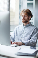 graphic vertical portrait of bearded adult man using computer at workplace in it office against wind
