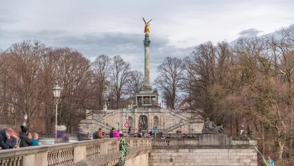 Wall Mural - Peace Column with golden Angel of Peace statue (Friedensengel) timelapse, people on the bridge over Isar river looking to rope walker. Public park in the Bavarian capital. Germany, Munich, Bogenhausen