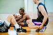 © Marko Geber - Young people taking a break from playing basketball in an indoor basketball gym