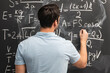 © Vitaliy - Physics teacher writes various formulas on the blackboard