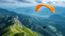 Single Paraglider On An Orange Paragliding Flies Over Green Mountains And Beautiful Landscapes At Sunny Day