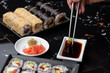 Close up of hands with chopsticks eating japanese food. Traditional asian rolls. Maki sushi with vegetables and tuna