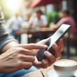 © Rezhwan - A man's hands using a smartphone at an outdoor cafe table, with a cup of latte art coffee, in a casual urban setting.