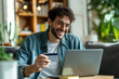 © Jan - Smiling man with glasses making an online payment on a laptop with a credit card