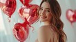A happy woman with chic long hair in a beautiful evening dress and makeup stands next to a heart-shaped balloons, white romantic background, Valentine's Day celebration