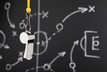 Wall Mural - Referee whistle against chalkboard with game scheme, closeup. Space for text