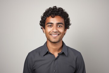 Wall Mural - Portrait of a happy young indian man looking at camera against grey background